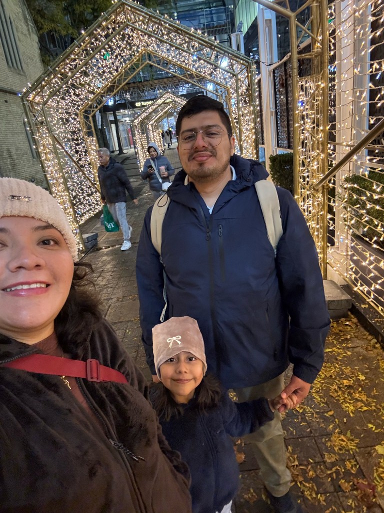 Paloma, Edgar y una niña bajo luces navideñas